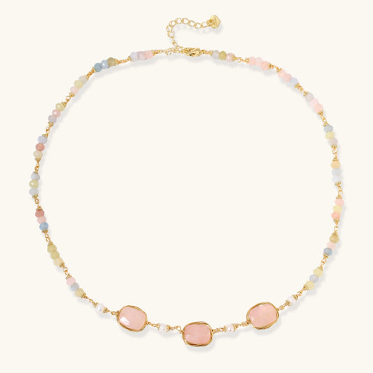Gold necklace with three rose quartz stones, multicolor pastel beads, and pearl accents on white background.