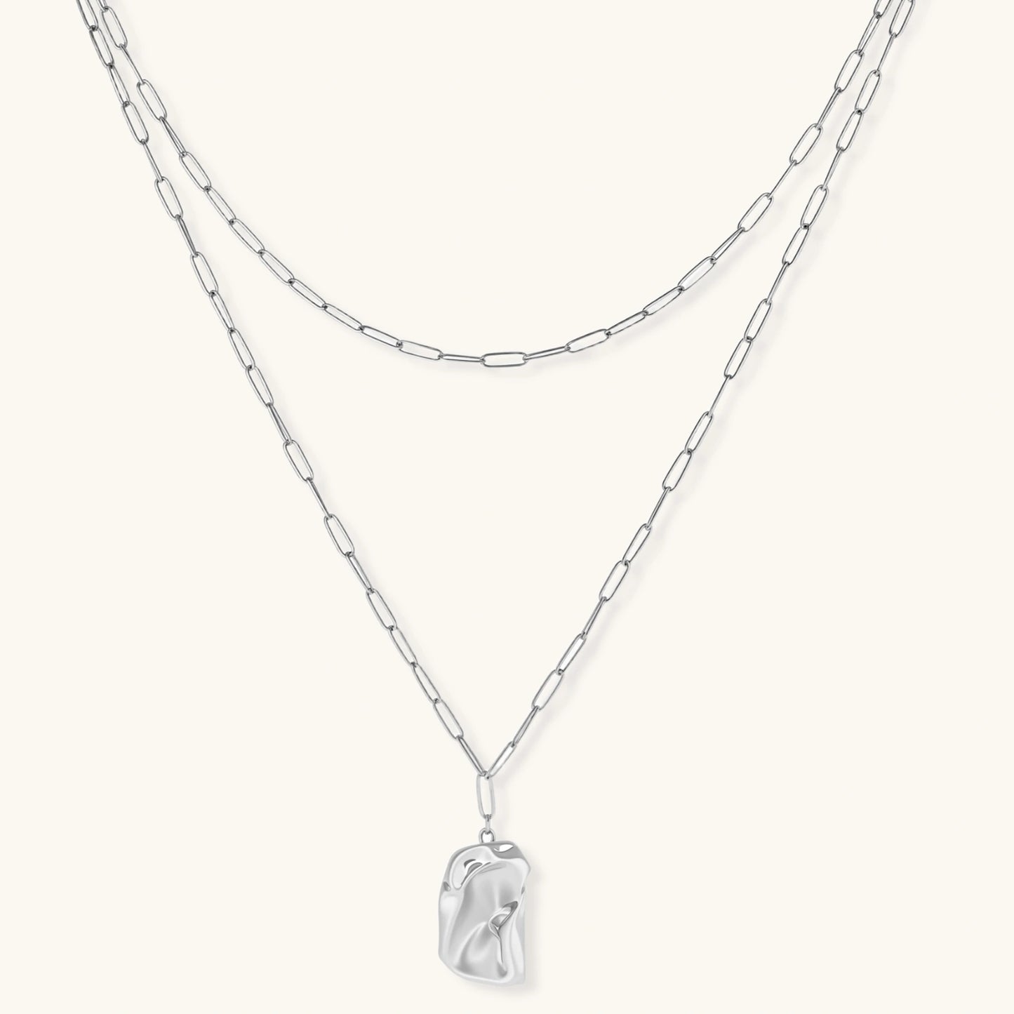 Silver layered necklace with organic flowing pendant in eco-zinc alloy on neutral background, showing adjustable chain design.