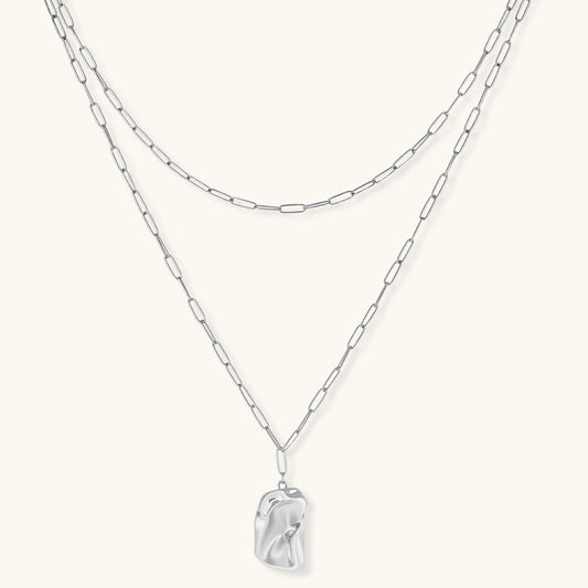 Silver layered necklace with organic flowing pendant in eco-zinc alloy on neutral background, showing adjustable chain design.
